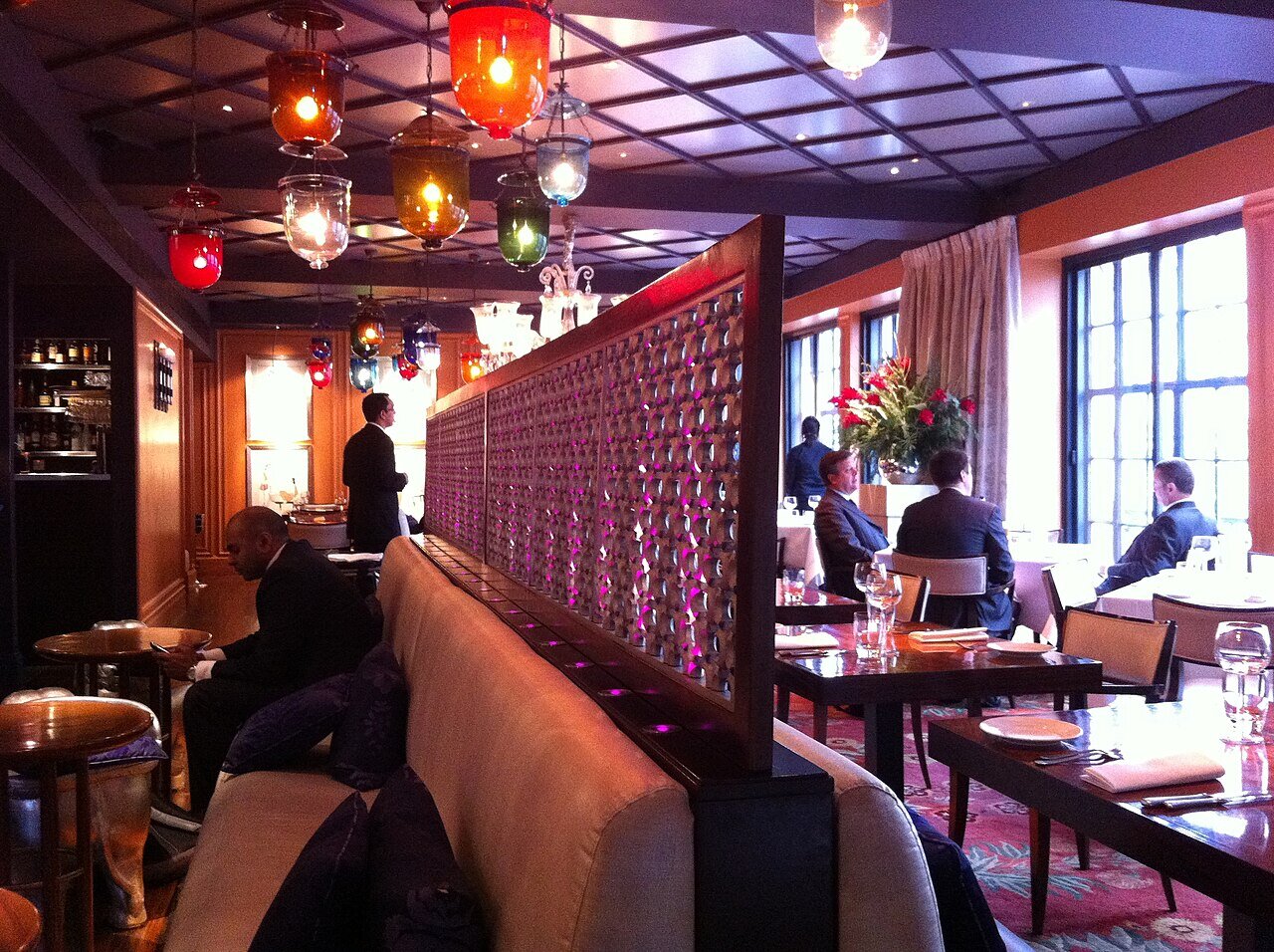 The first-floor dining room at Veeraswamy, with coloured glass lanterns hanging over banquettes and tables by tall windows