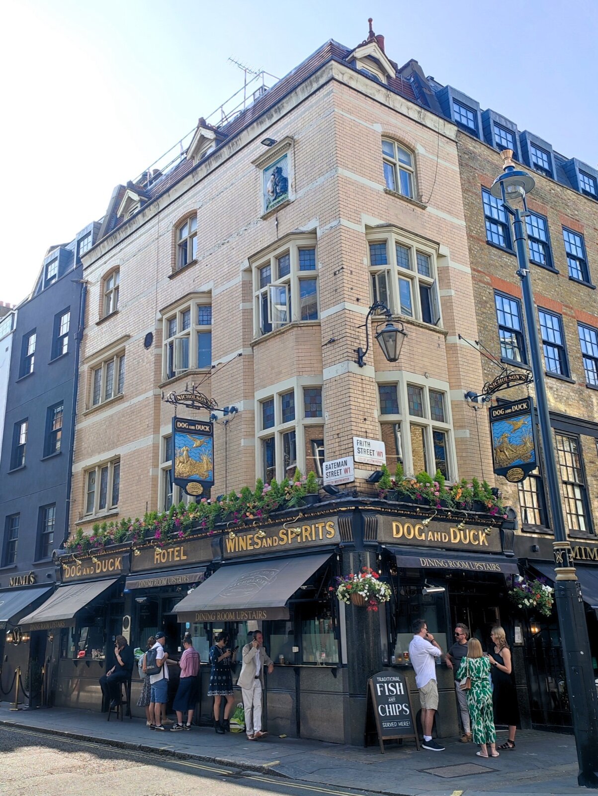The four-storey Dog and Duck pub on a Soho street corner, with its name in gold letters over the ground floor and drinkers standing outside
