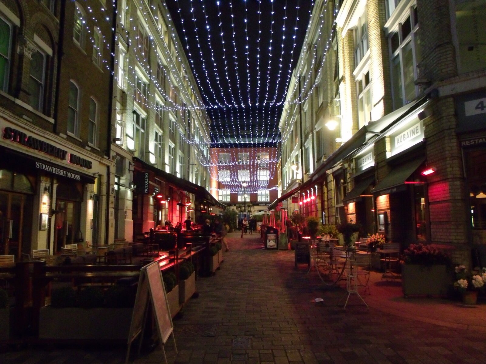 Heddon Street in Mayfair at night, a narrow pedestrian lane of restaurants with outdoor tables under a canopy of string lights
