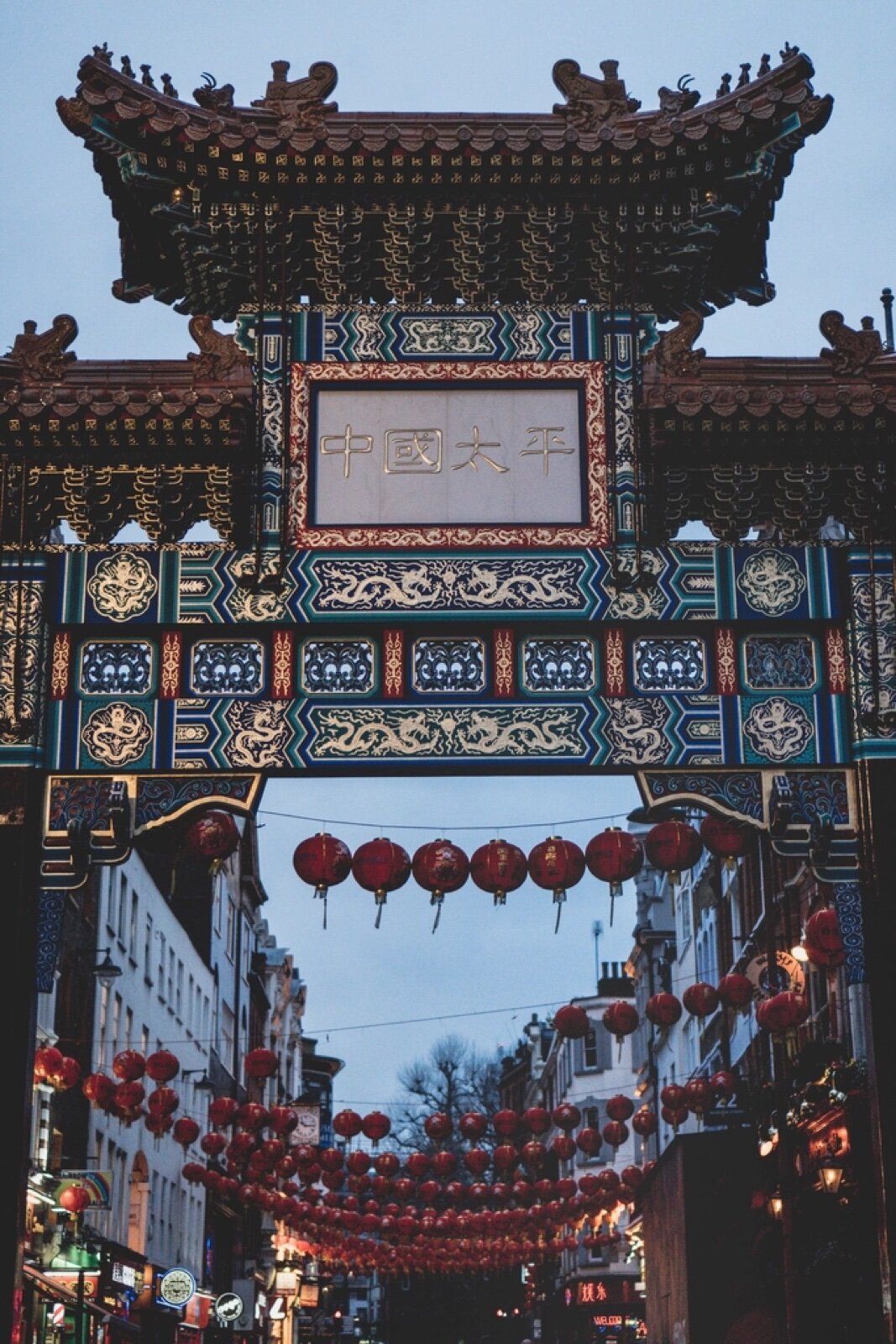The ornamental Chinese gate on Wardour Street with red lanterns strung along Gerrard Street behind it