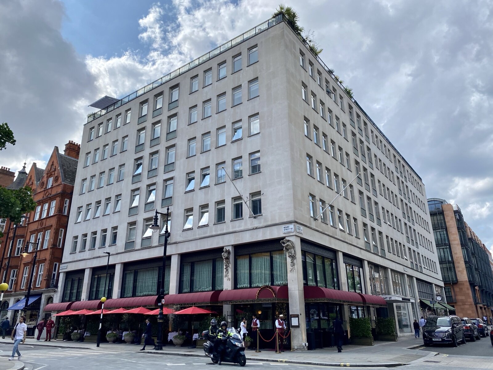 The corner of Mount Street and Davies Street in Mayfair, with awnings over pavement tables below a stone-faced building